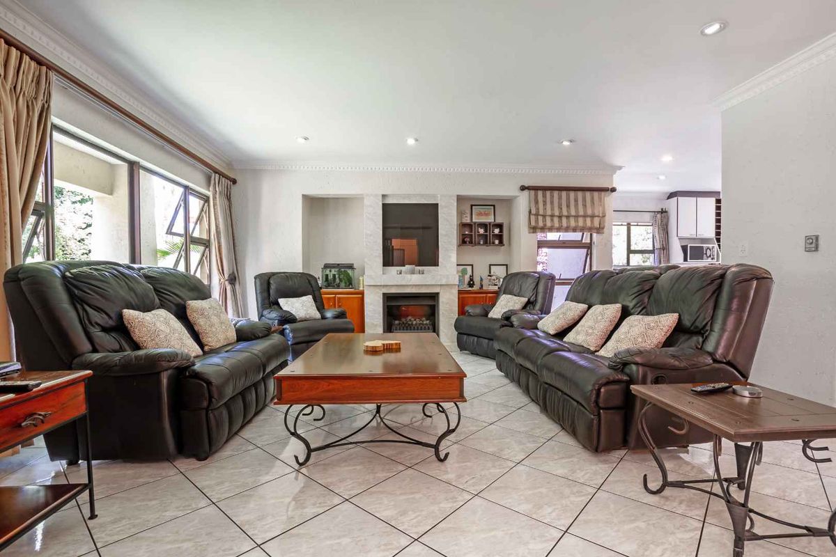 Spacious living room featuring tiled flooring, a built-in fireplace with stone surround, and recessed ceiling lighting.