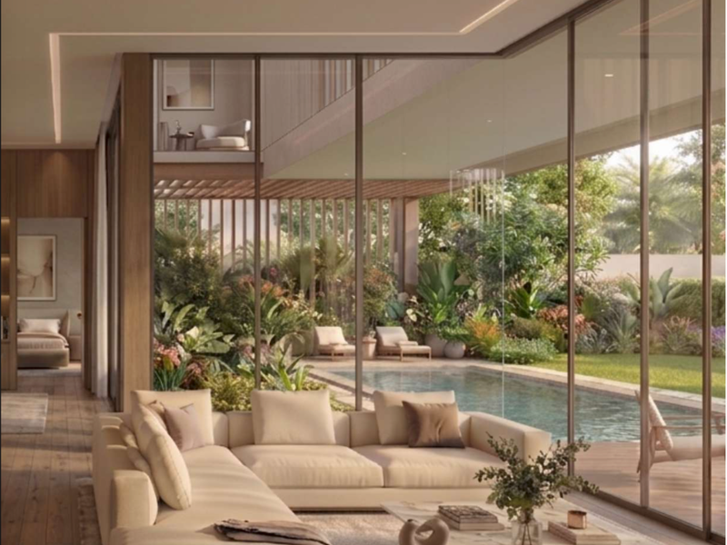 Modern open-plan living area featuring floor-to-ceiling glass walls, recessed lighting, and seamless transition to a private outdoor pool and garden terrace.