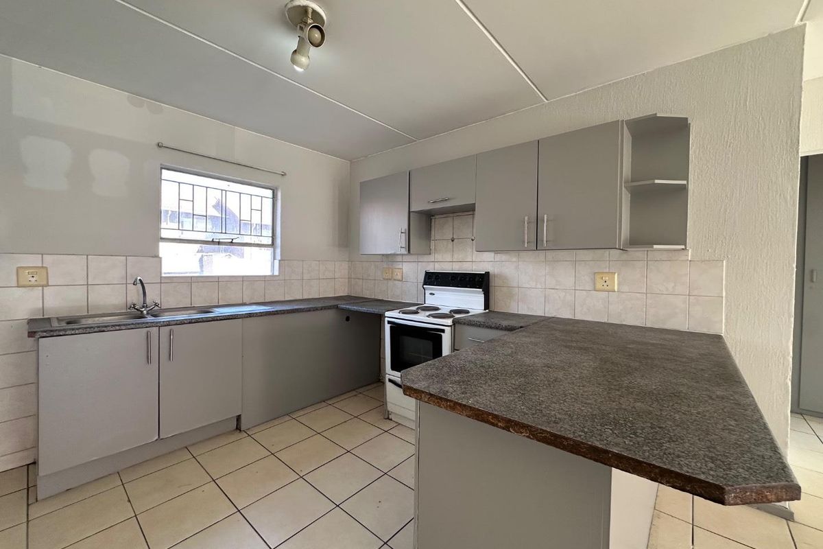 A functional kitchen featuring grey built-in cabinetry, laminate countertops, a tiled backsplash, and a freestanding stove, ready for personal touches.