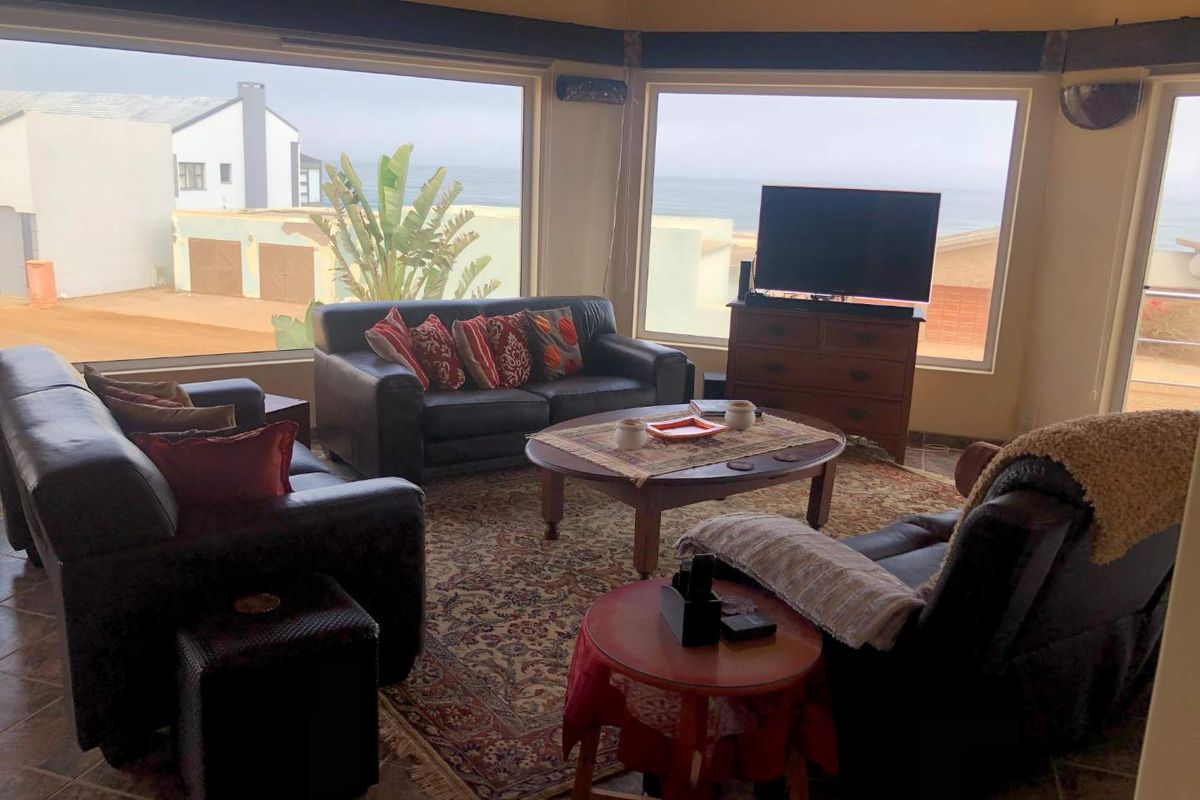 Spacious living room featuring large windows with ocean views, tiled flooring, and ample natural light.
