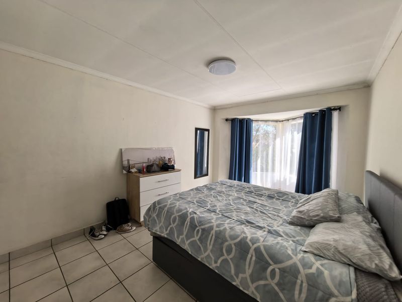 A bedroom featuring tiled flooring and a bay window, providing natural light. The space is functional with standard finishes.