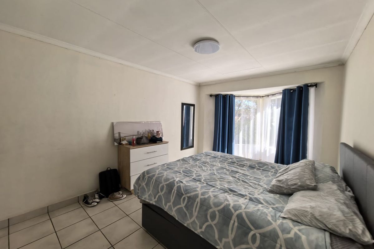 A bedroom featuring tiled flooring and a bay window, providing natural light. The space is functional with standard finishes.