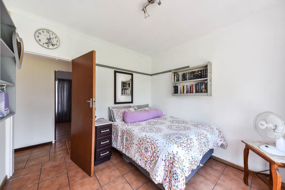 A functional bedroom featuring tiled flooring and built-in wall shelving, providing a practical and comfortable living space.