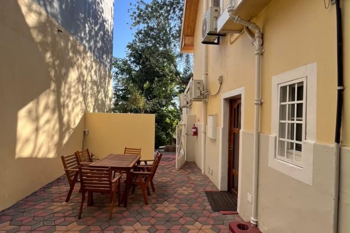 A paved rear courtyard area featuring external air conditioning units, drainage infrastructure, and access to the building exterior.
