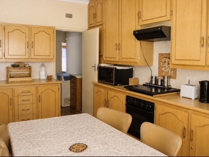 A functional kitchen featuring traditional wooden cabinetry, built-in oven, electric hob, and extractor fan, offering a classic layout with ample storage space.