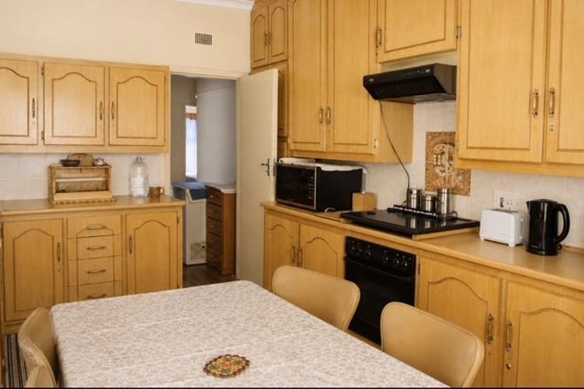 A functional kitchen featuring traditional wooden cabinetry, built-in oven, electric hob, and extractor fan, offering a classic layout with ample storage space.