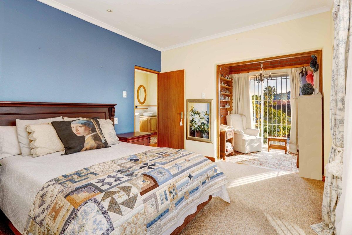Spacious bedroom featuring an en-suite bathroom and an adjoining sunroom with large windows and security bars, offering natural light and a functional layout.