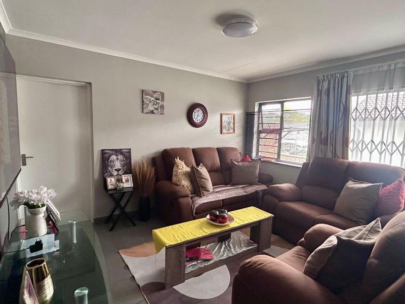 A comfortable living room featuring tiled flooring, security gates on the windows, and neutral wall finishes.