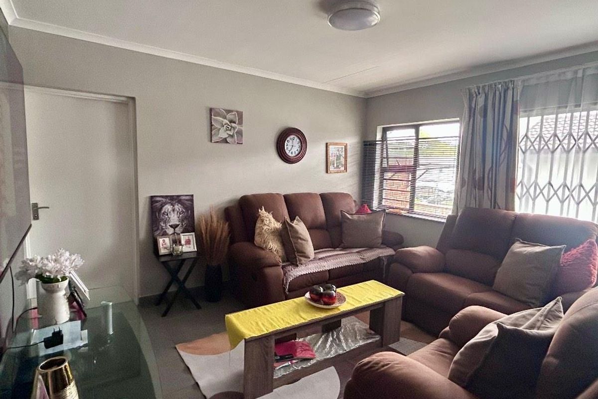 A comfortable living room featuring tiled flooring, security gates on the windows, and neutral wall finishes.