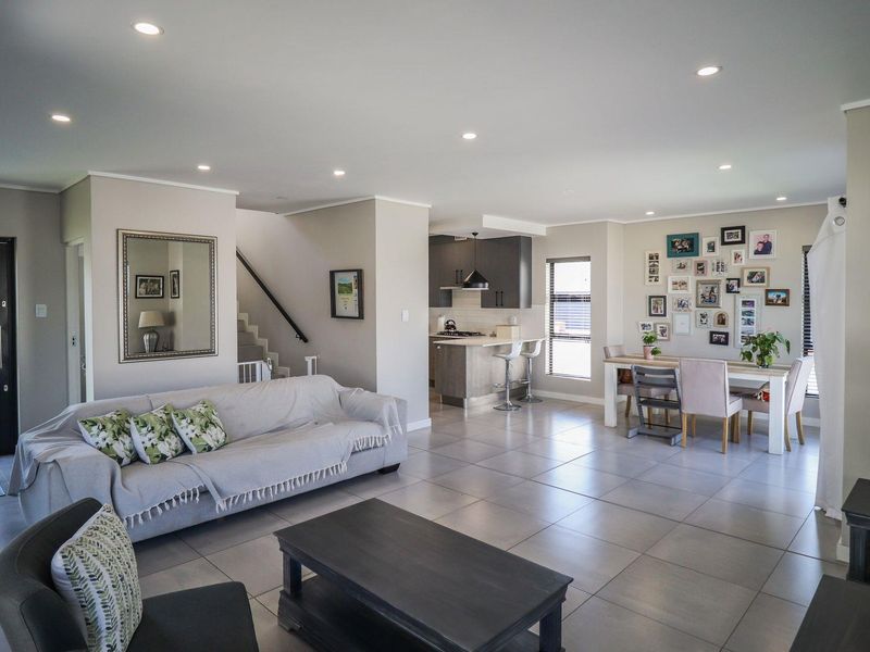 Spacious open-plan living area featuring tiled floors, recessed lighting, and a modern kitchen with integrated cabinetry, flowing seamlessly into the dining and lounge spaces.