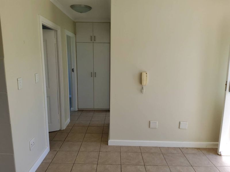 A clean, neutral hallway featuring tiled flooring, built-in storage cupboards, and an integrated intercom system, providing a functional transition space within the townhouse.