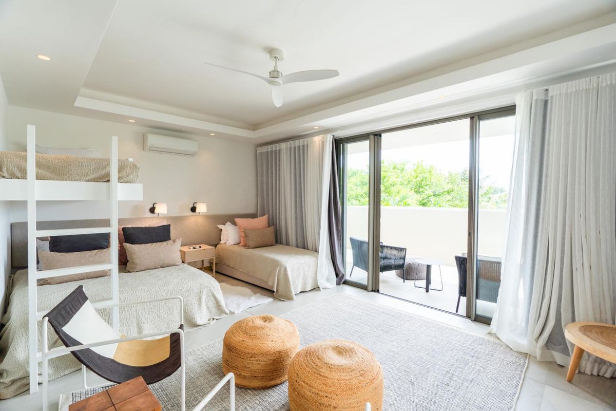 Spacious bedroom featuring a ceiling fan, wall-mounted air conditioning unit, and large sliding glass doors opening onto a private balcony.