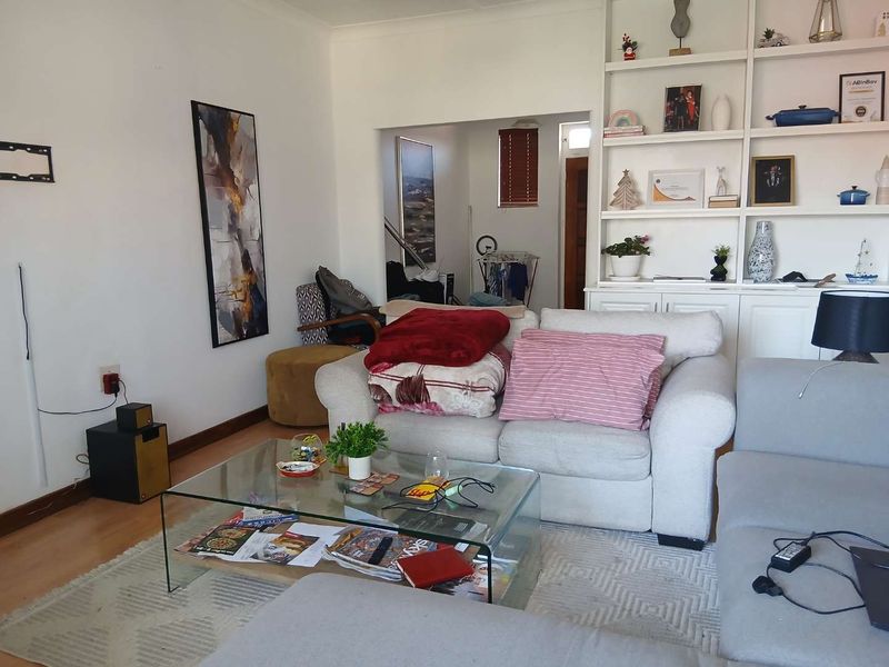 A comfortable living room featuring a large built-in shelving unit and laminate flooring, offering a functional space with potential for modern updates.
