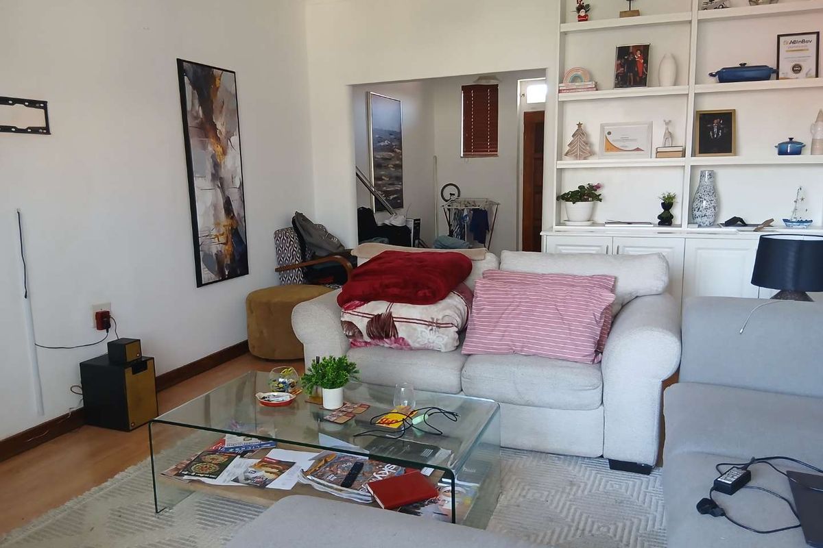 A comfortable living room featuring a large built-in shelving unit and laminate flooring, offering a functional space with potential for modern updates.