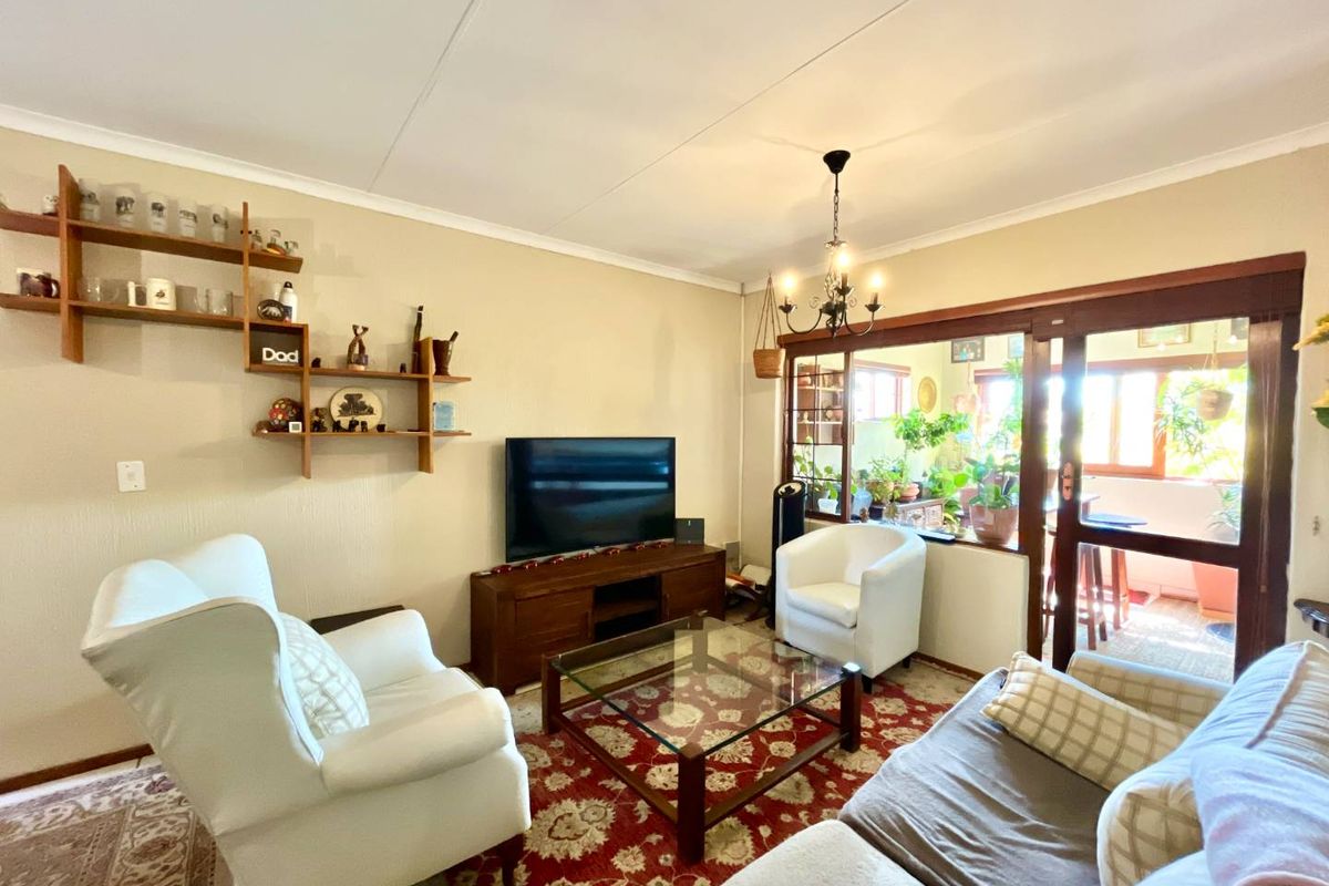 A comfortable living room featuring a coved ceiling, a central chandelier, and large sliding glass doors that provide access to an adjoining patio area.