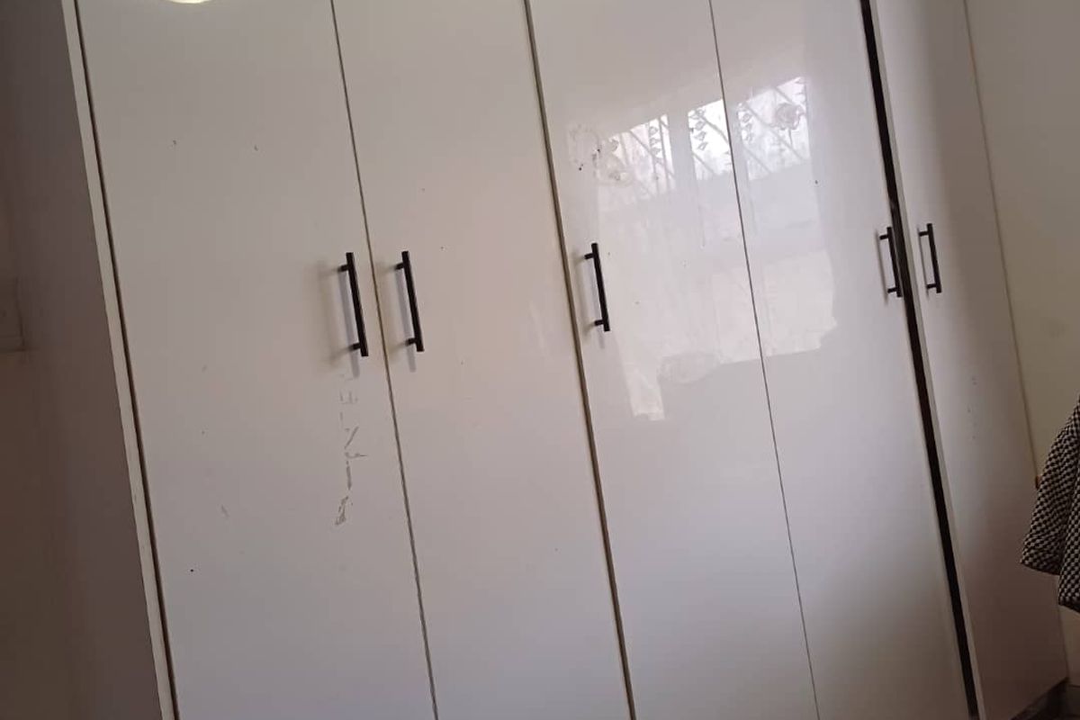A bedroom featuring built-in white high-gloss wardrobes with modern black handles.
