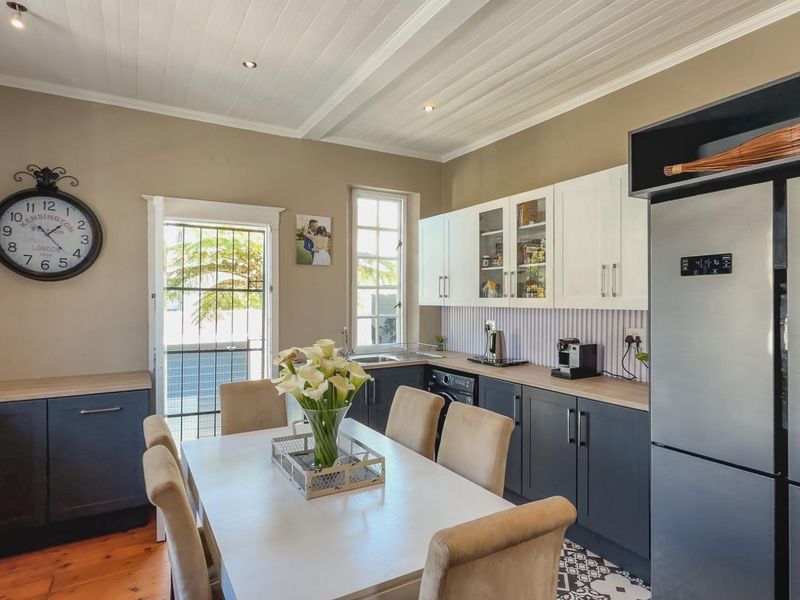 A well-maintained kitchen featuring two-tone cabinetry, laminate countertops, and a mix of timber and tiled flooring, with direct access to the exterior.