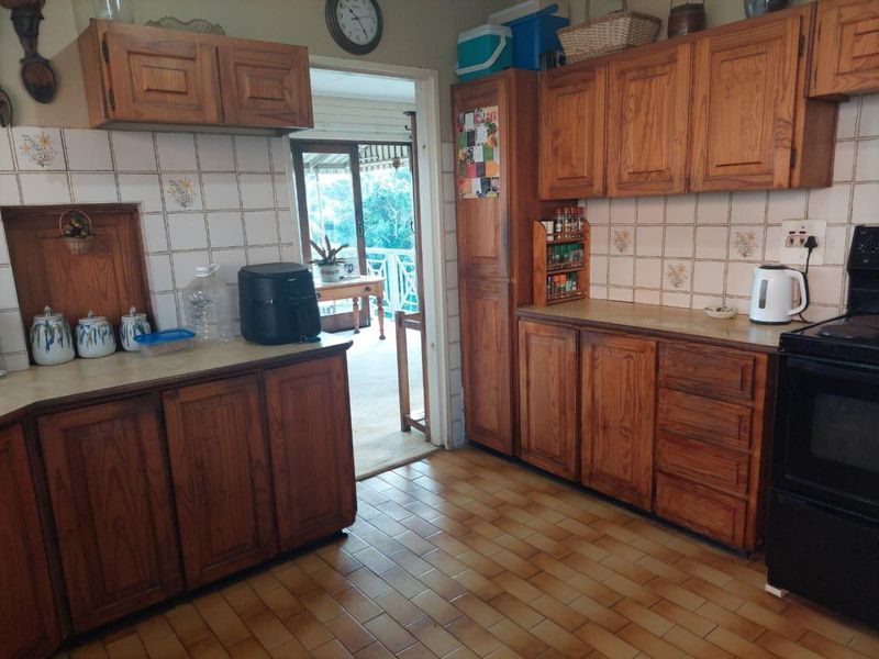 A functional kitchen featuring traditional wooden cabinetry, laminate countertops, and ceramic tile flooring, with direct access to an outdoor patio area.