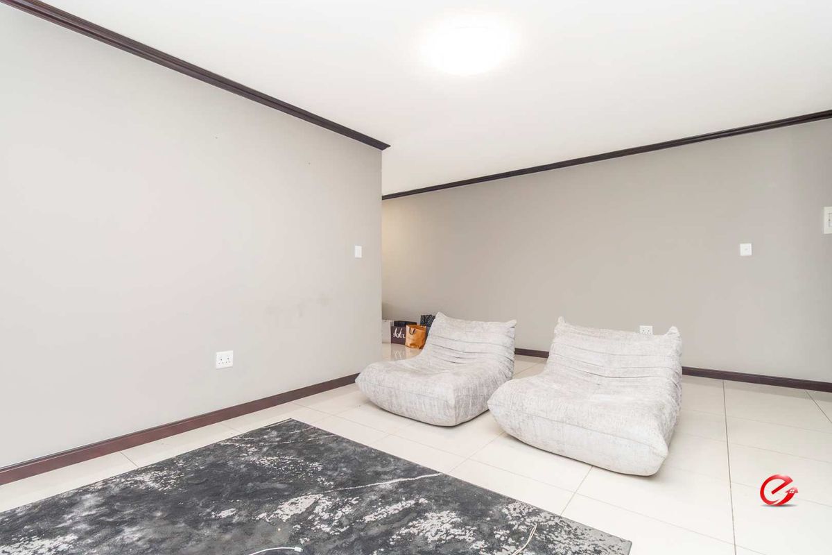 A spacious living area featuring neutral wall tones, tiled flooring, and dark trim detailing, providing a versatile space for relaxation.