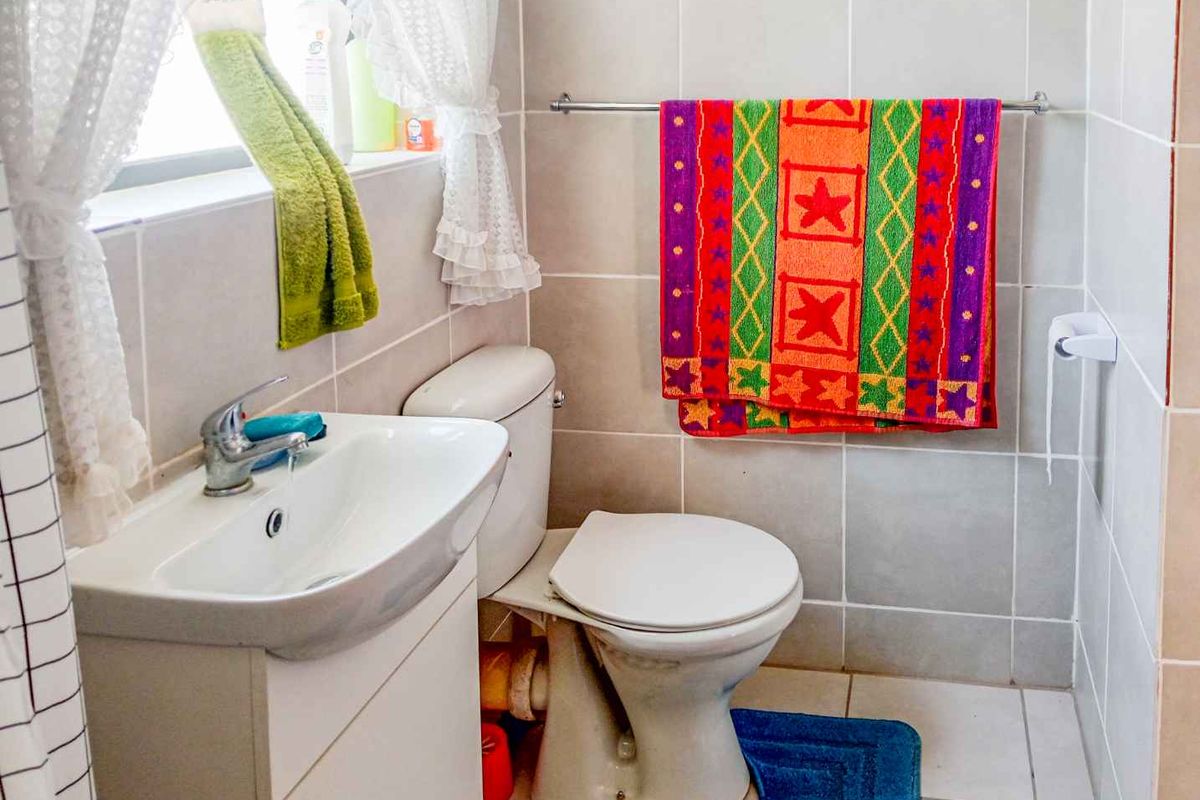 A functional bathroom featuring a vanity basin, toilet, and neutral wall and floor tiling.