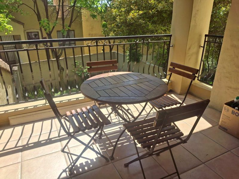 A covered balcony featuring tiled flooring and a wrought iron railing, providing a pleasant outdoor space for relaxation.