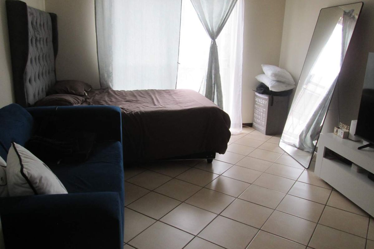 A bedroom featuring tiled flooring and a large sliding glass door providing access to an outdoor area.