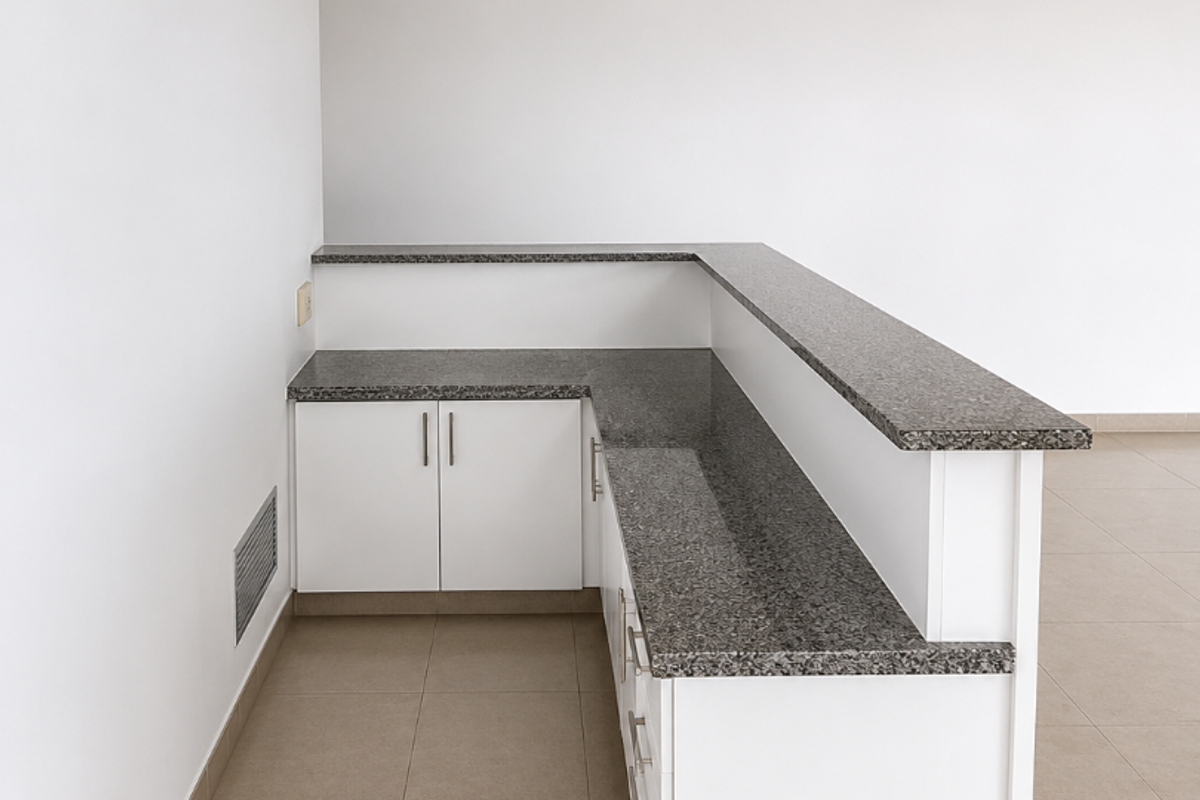 A clean, empty office space featuring a built-in reception desk with granite countertops, tiled flooring, and a professional drop ceiling with recessed lighting.
