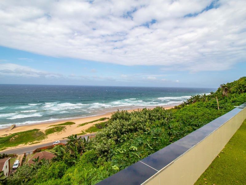 Elevated outdoor terrace featuring a modern balustrade with expansive, unobstructed panoramic views of the coastline and ocean.