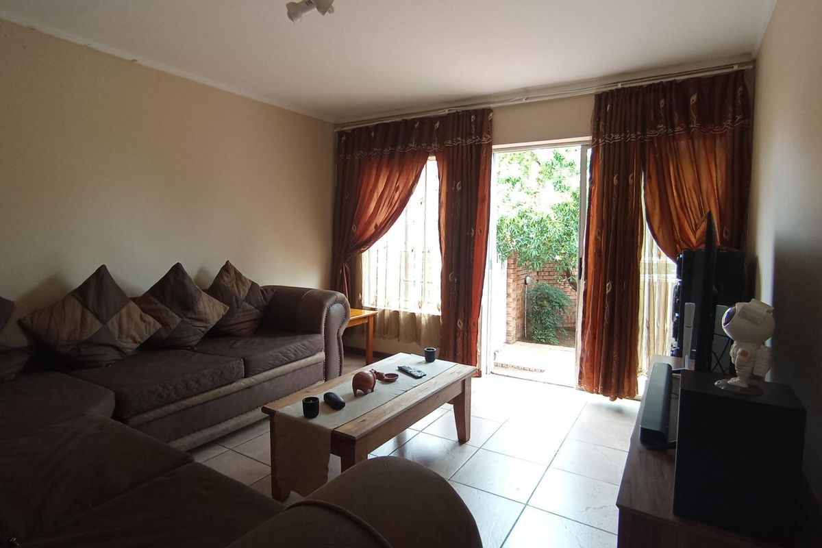 A living room featuring tiled flooring and a sliding glass door providing direct access to an outdoor patio area.