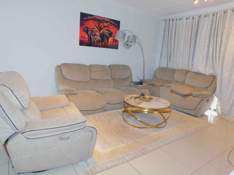 A living room area featuring neutral tiled flooring and window treatments, providing a functional space for relaxation.