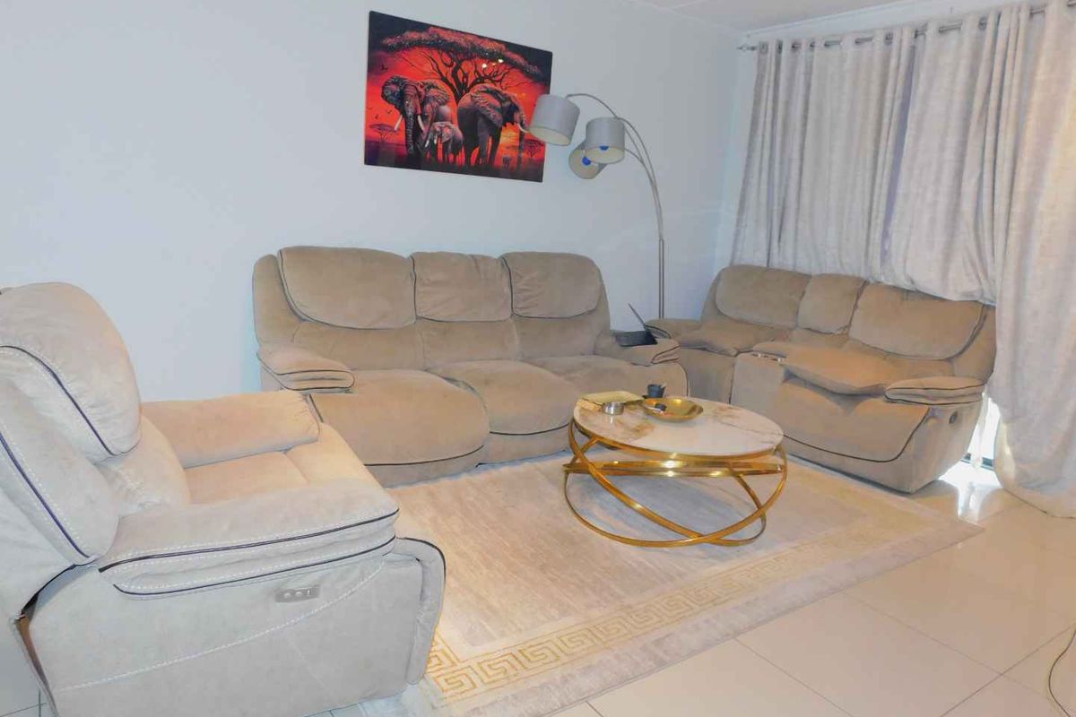 A living room area featuring neutral tiled flooring and window treatments, providing a functional space for relaxation.