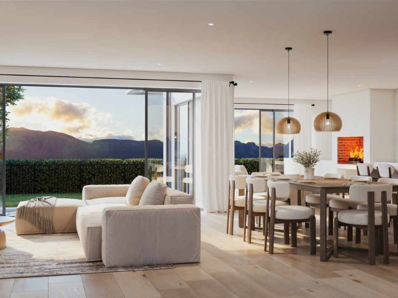 A modern open-plan living, dining, and kitchen area featuring high-end finishes, large sliding doors with mountain views, and a sleek, contemporary design.