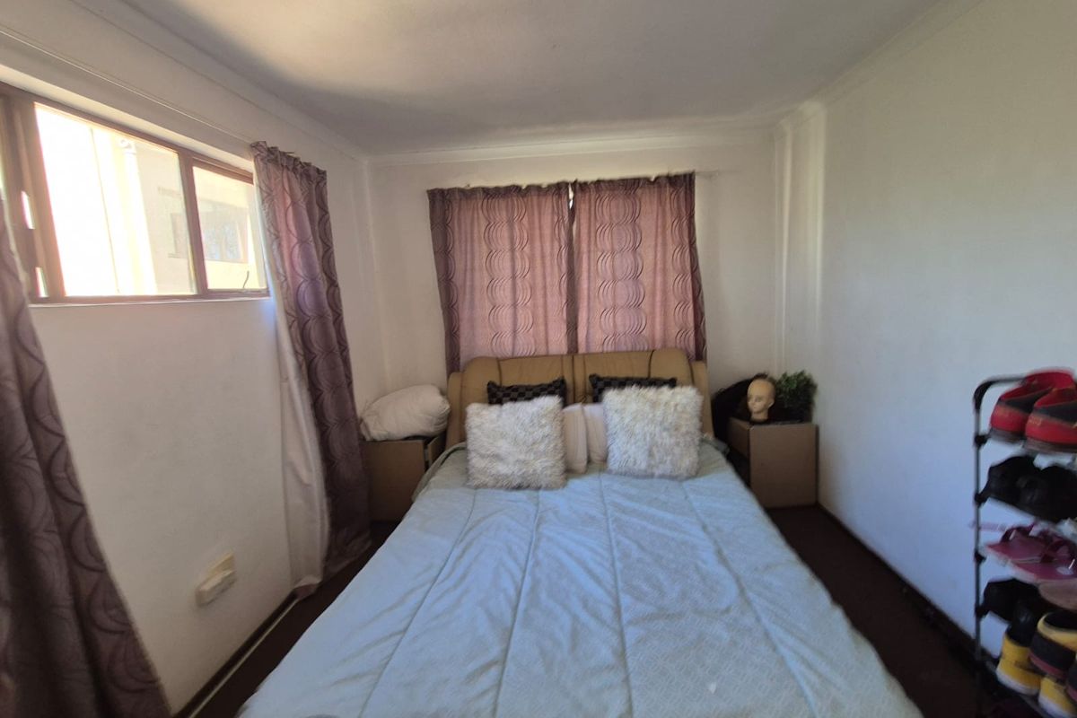 A standard bedroom featuring neutral walls, coving, and natural light from side windows. The space offers a functional layout for a comfortable sleeping area.