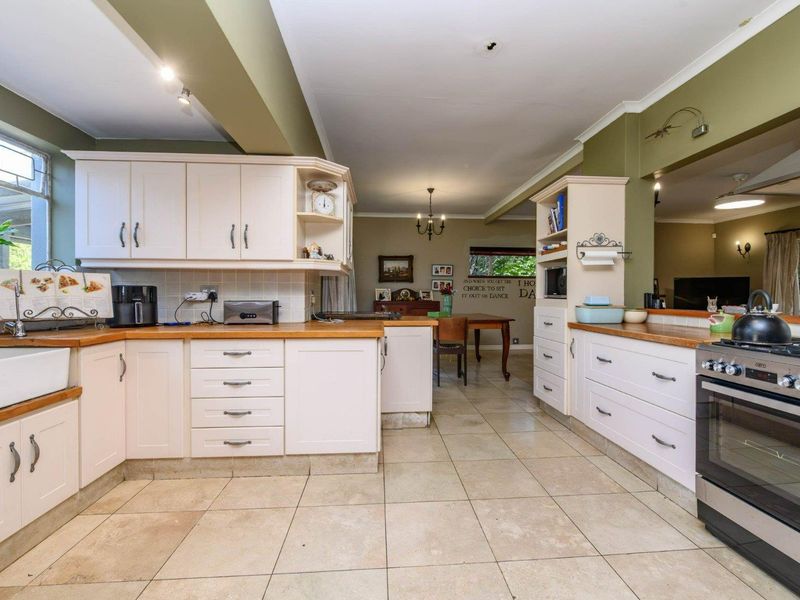 Spacious kitchen featuring farmhouse sink, wooden countertops, gas stove, and ample built-in cabinetry, flowing into an open-plan dining area.