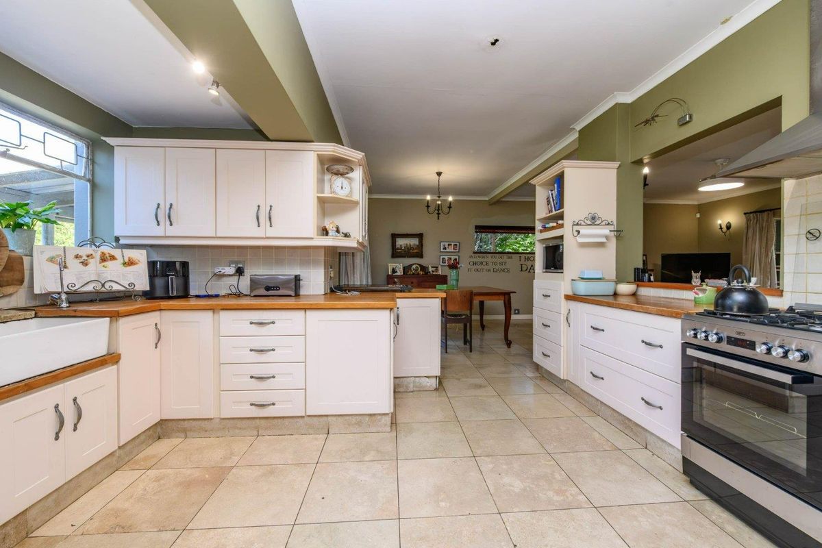Spacious kitchen featuring farmhouse sink, wooden countertops, gas stove, and ample built-in cabinetry, flowing into an open-plan dining area.