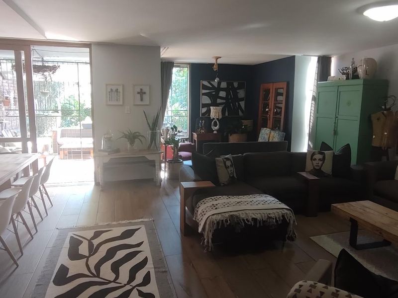 Spacious open-plan living and dining area featuring timber flooring, modern pendant lighting, and large sliding glass doors leading to an outdoor patio.