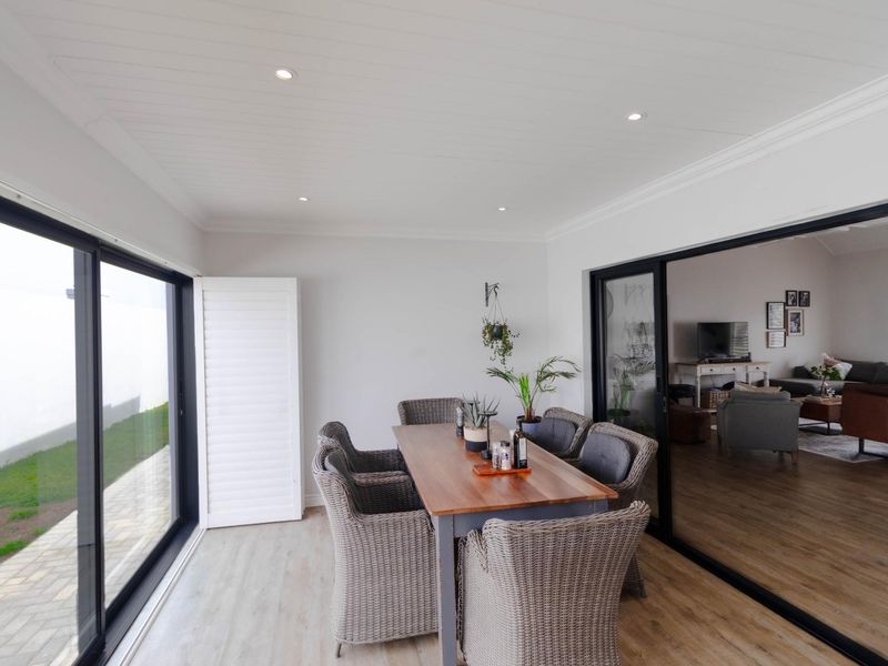 A bright, enclosed patio area featuring modern sliding glass doors, recessed lighting, and timber-look flooring, offering a seamless transition to the outdoor space.