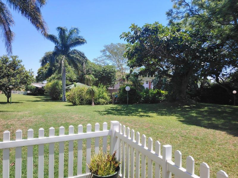 A well-maintained garden area featuring a white picket fence, mature trees, and established lawn, providing a pleasant outdoor space.