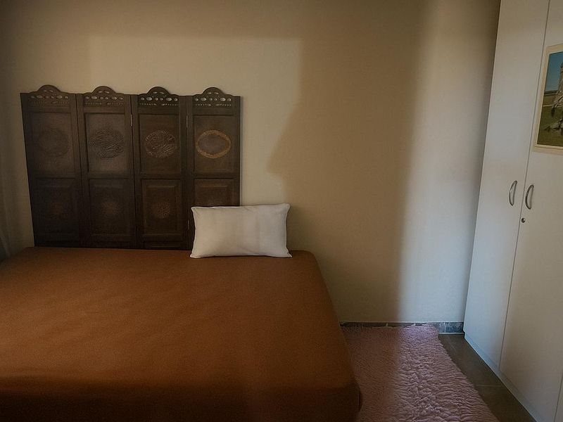 A bedroom featuring a built-in wardrobe and a drop ceiling, providing functional storage and standard finishes.