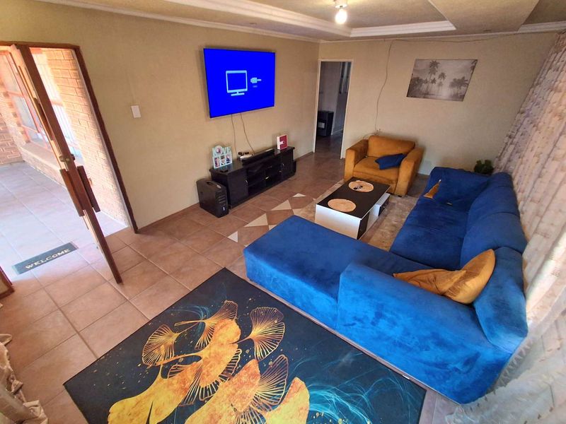 A comfortable living room featuring tiled flooring, a recessed ceiling, and an exposed brick accent wall, providing a functional and inviting space.