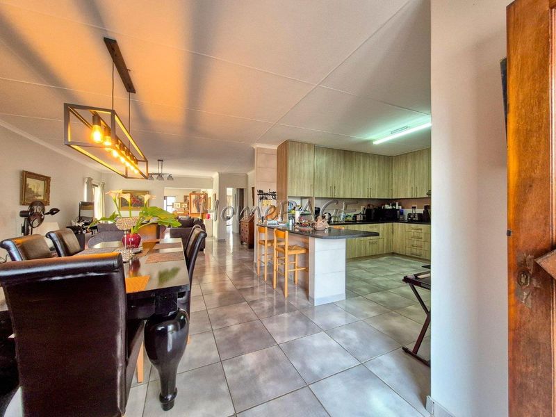 Spacious open-plan living and dining area featuring a modern kitchen with ample cabinetry, a central island, and tiled flooring throughout.