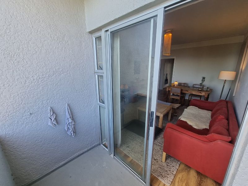 A compact balcony area featuring a sliding glass door providing access to the interior living space.