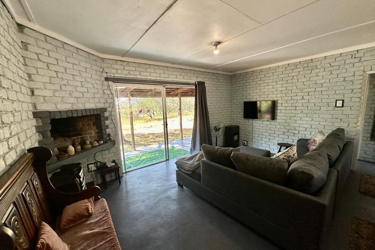 Living room featuring painted brick walls, a built-in fireplace, and sliding glass doors providing access to the outdoor area.