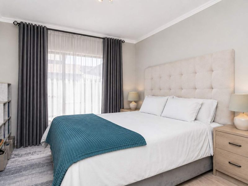 A well-maintained bedroom featuring neutral wall finishes, coving, and large windows with installed curtain tracks.