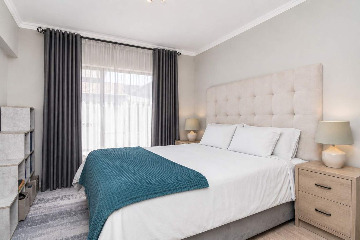 A well-maintained bedroom featuring neutral wall finishes, coving, and large windows with installed curtain tracks.