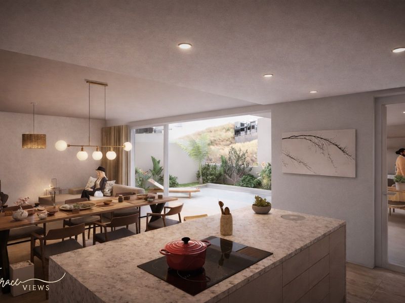 Modern open-plan living area featuring a kitchen island with stone countertops, induction cooktop, and seamless flow to an outdoor patio through sliding glass doors.