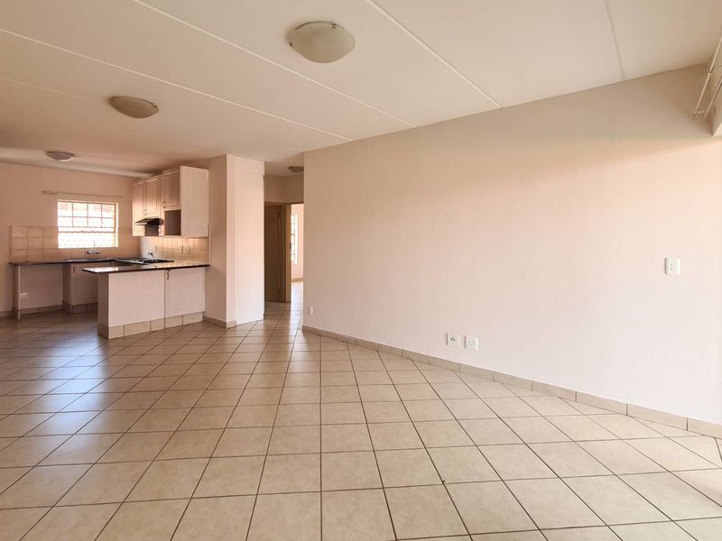 Spacious open-plan living and kitchen area featuring neutral tiled flooring, built-in cabinetry, and large sliding doors providing access to the exterior.