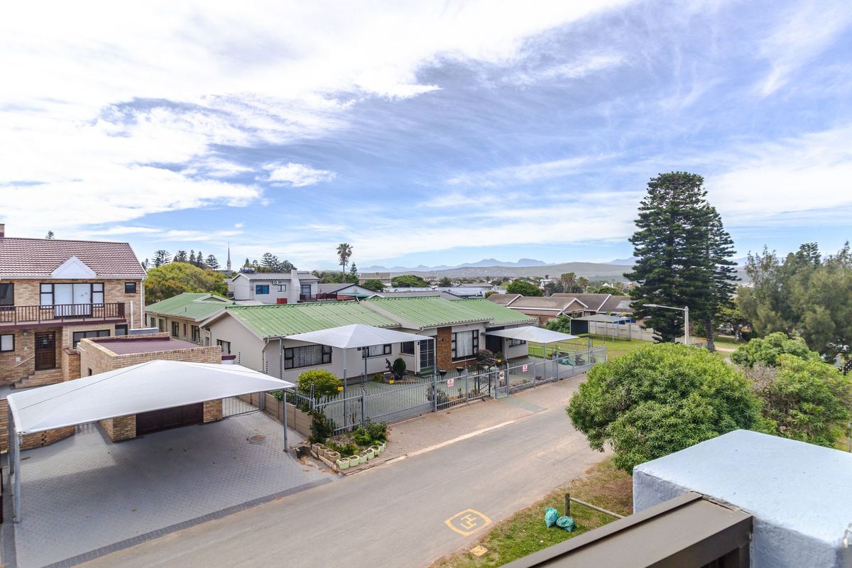 An elevated aerial view of the apartment complex, featuring paved driveways, shade cloth carports, and surrounding residential neighborhood landscape.