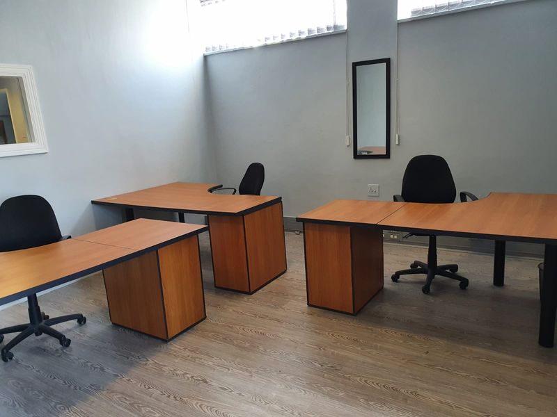 A functional office space featuring laminate flooring and high-level windows, providing a practical work environment.