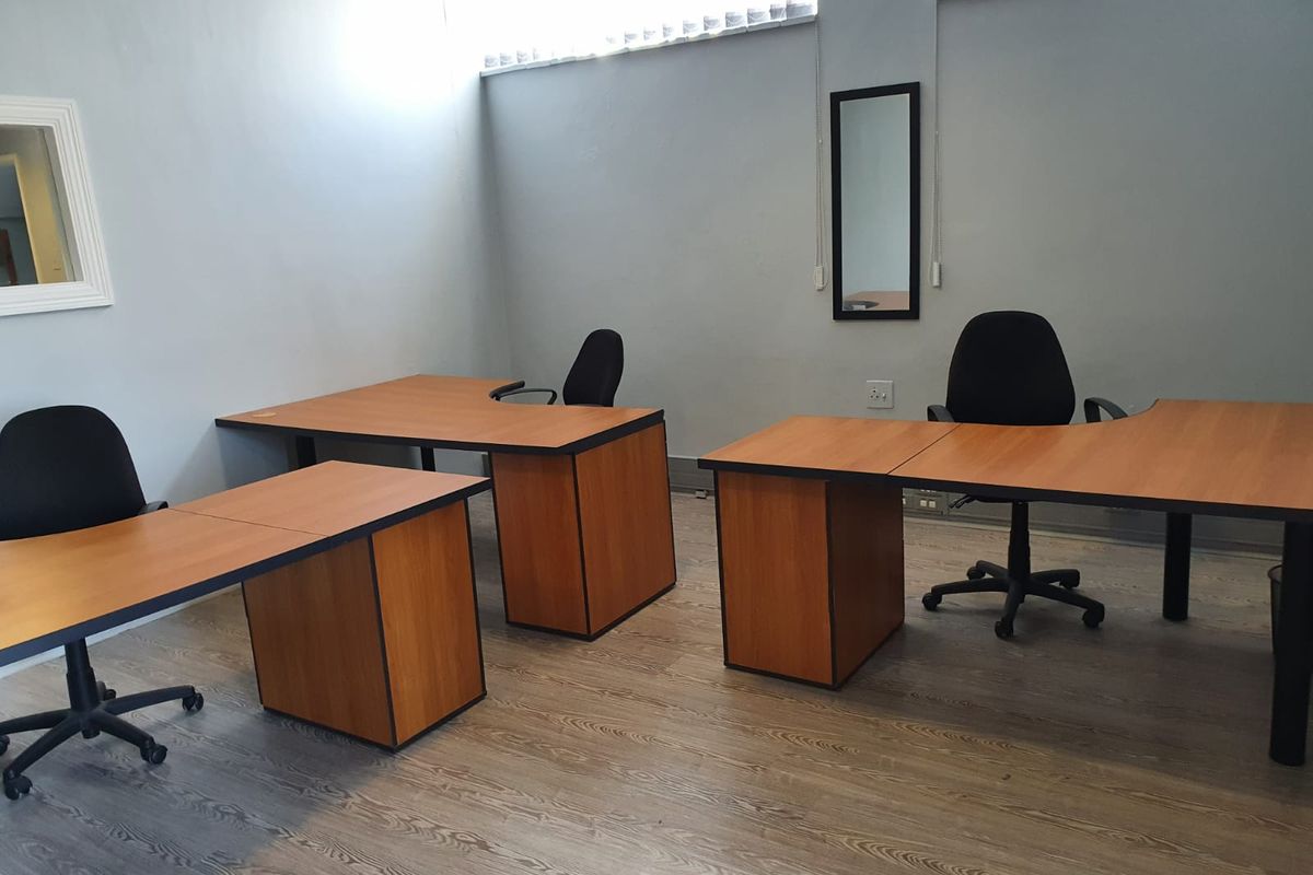 A functional office space featuring laminate flooring and high-level windows, providing a practical work environment.